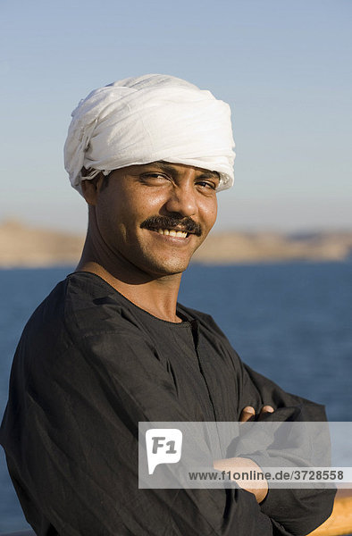 Smiling Nubian man with turban and Galabiya  Lake Nasser at back  Egypt