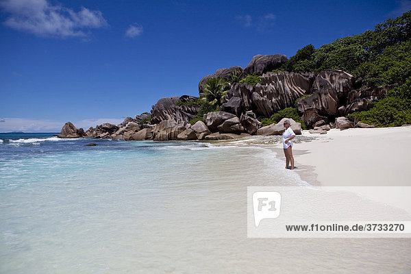 Woman standing on the beach of Grand Anse  with the typical granite rocks of La Digue  Indian Ocean  La Digue Island  Seychelles  Indian Ocean  Africa