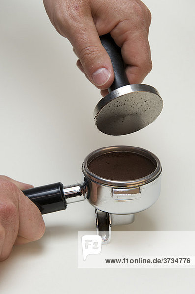 Professionelle Zubereitung von Espresso mit einer Siebträgermaschine: Nach dem Glattdrücken wird der Tamper wieder aus dem Siebträger entfernt