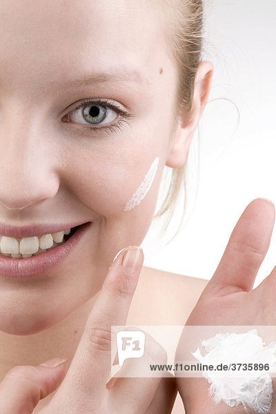Young woman applying face cream