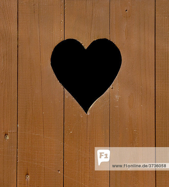 Wooden door of a toilet hut heart-shaped window close-up