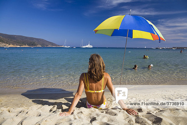Frau sitzt am Strand von Marina di Campo  Elba  Toskana  Italien  Mittelmeer  Europa