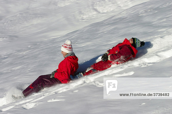 Zwei Mädchen  9 und 12 Jahre alt  reiten auf Schlitten  Dolomiten  Italien  Europa