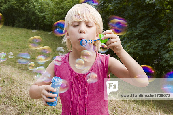 Blondes 7-jähriges Mädchen mit Seifenblasen