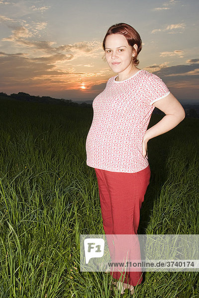 28-jährige schwangere Frau vor einem Sonnenuntergang