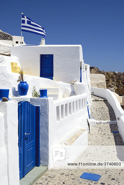 Hauseingang mit blauer Tür  enger Gang und griechische Fahne  Oia  Santorin  Santorini  Kykladen  Griechenland  Europa