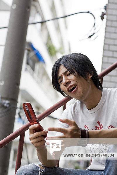 Young man playing a game on a mobile phone  Tokyo  Japan  Asia