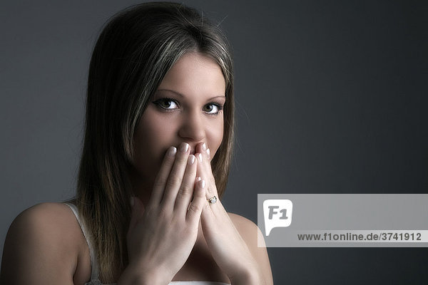 Young woman holding her hands in front of her mouth in shame