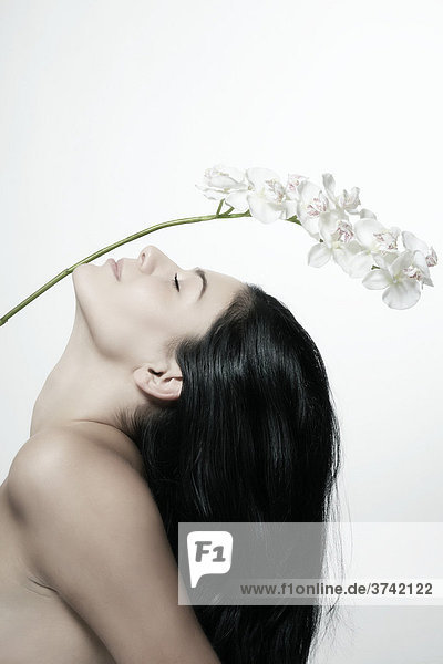 Dark haired young woman stretching under flower blossoms  portrait