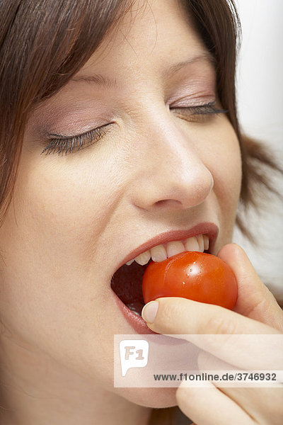 Frau beißt in Cherry Tomate