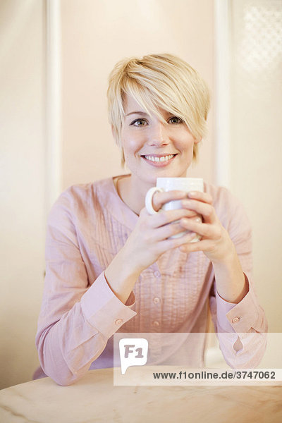 Young woman with short blonde hair drinking coffee