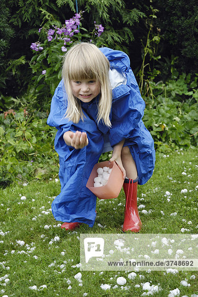 Blonde girl  6 years old  collecting hailstones after a storm  11.8.2008  Nicklheim  Bavaria  Germany  Europe