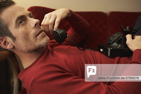 Man on couch using vintage phone