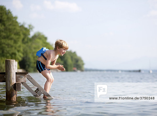 Boy jumping in water with swimming belt
