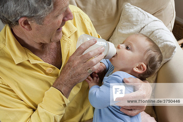 Opa füttert Enkel Milchflasche