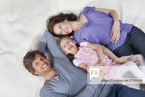 Glückliche Familie auf dem Teppich liegend