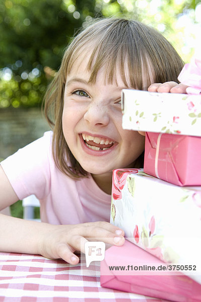 Ein fröhliches kleines Mädchen  das gerade Geschenke aufmacht.