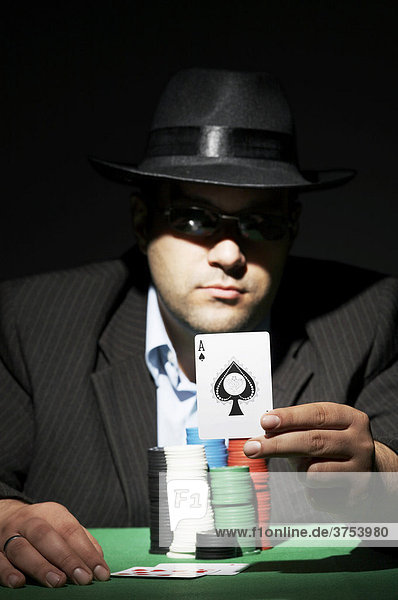 Pokerspieler mit Sonnenbrille zeigt die Spielkarte Ass