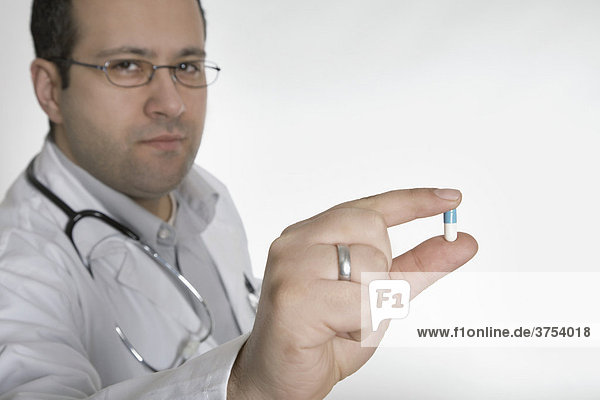 Arzt mit Stethoskop hält Pille nach vorn