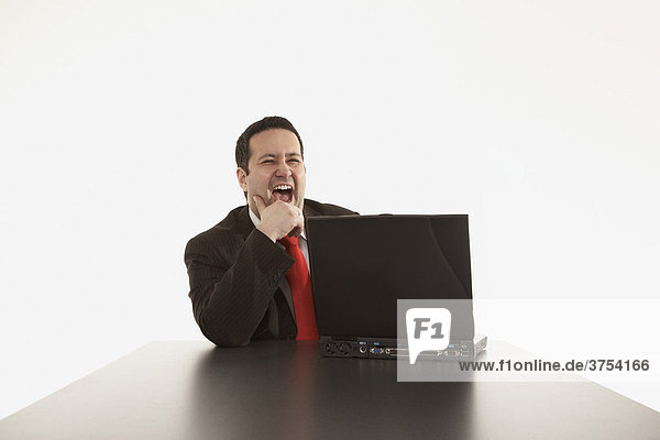 Geschäftsmann lacht hinter seinem Laptop