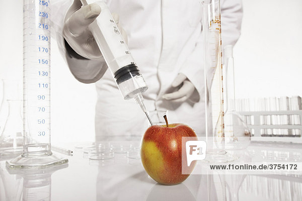 Chemiker spritzt Substanz in einen Apfel