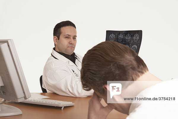 Arzt mit Stethoskop gibt anhand einer CT Aufnahme einem Patienten seine Diagnose