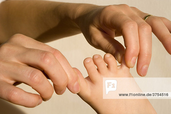 Woman's hands tugging at child's toes