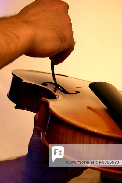 Geigenbauer prüft und verändert die Position des Stimmstocks