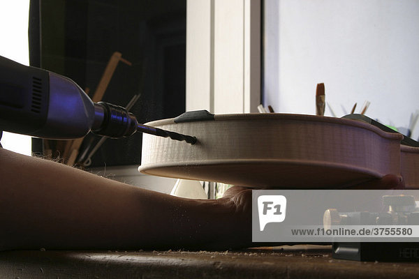 Geigenbauer bohrt Loch für die Endkugel zum Befestigen des Saitenhalters