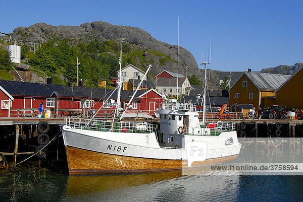 Schiff im kleinen Hafen mit roten Fischerhäusern  Rorbuer (Rorbu) Häuser von Nusfjord  Lofoten  Norwegen  Skandinavien