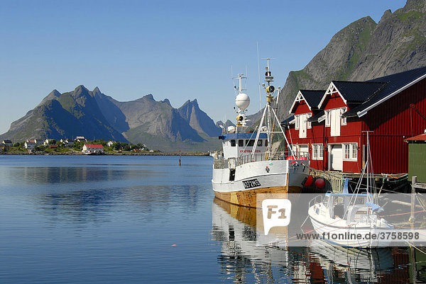 Blick über den Fjord mit Booten und Fischerhäusern  Rorbuer (Rorbu) Häuser auf die Berge von Moskenesoya  Reine Hamnöy  Lofoten  Norwegen  Skandinavien