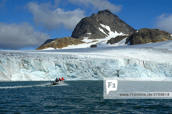 Small motorboat in front of a large ice wall or ice face  Apusiak Glacier and Mountains  eastern Greenland  Arctic