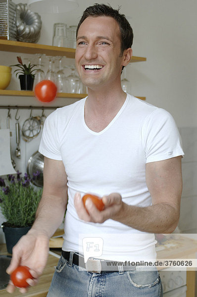 31-jähriger Mann jongliert Tomaten in Küche