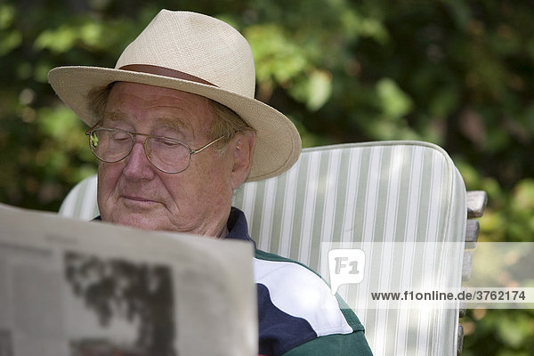 Ein Senior entspannt beim Zeitunglesen im Garten