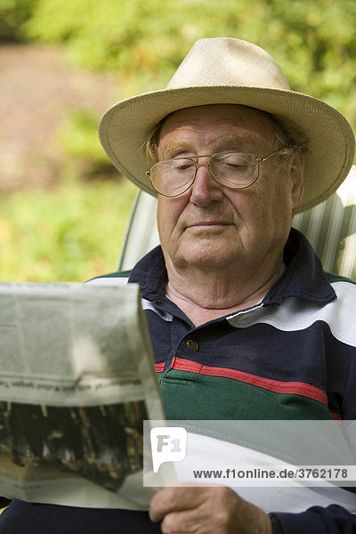 Ein Senior entspannt beim Zeitunglesen im Garten