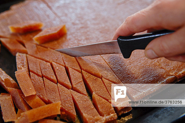 Frisches Quittenbrot wird mit einem Messer geschnitten