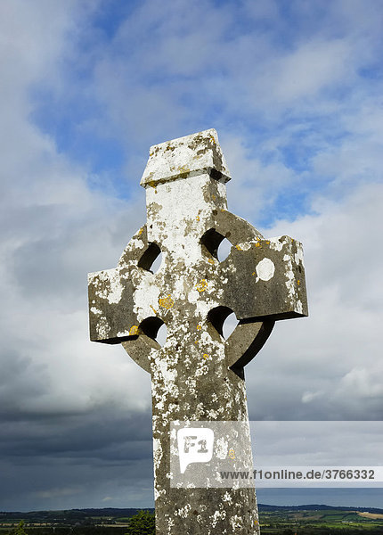Steinernes keltisches Kreuz mit Flechtenbesatz vor stimmungsvoller Bewölkung  Irland