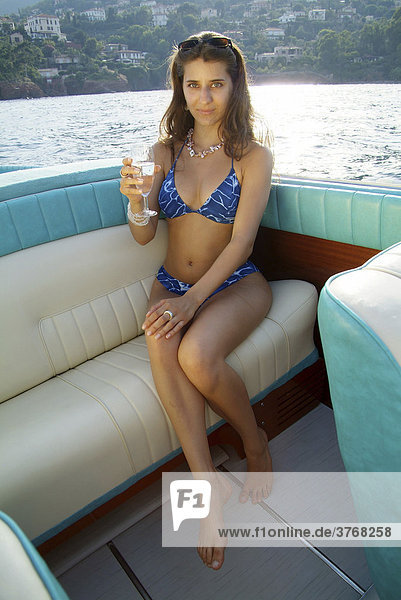 Junge Frau im Bikini mit einem Glas Sekt auf der Rückbank eines Riva Motorboots  ThÈoule-sur-Mer  Frankreich
