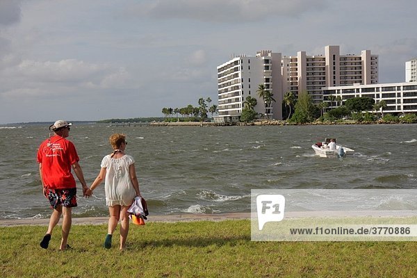 Florida  Fort Ft Myers  San Carlos Bay  Punta Rassa  waterfront  man  woman  couple  walking  choppy water  boat  building