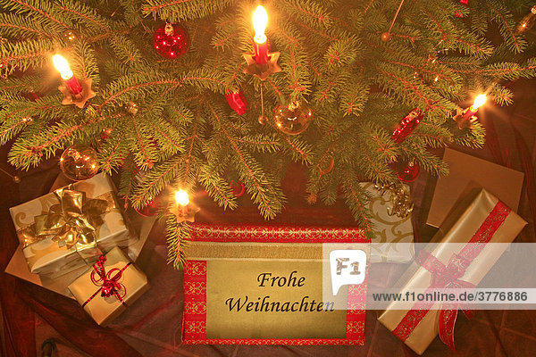 Geschmückter Weihnachtsbaum mit Kerzen und Porzellankugeln  Geschenke liegen unter dem Baum