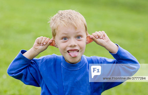 Ein Junge  5 Jahre  streckt seine Zunge heraus