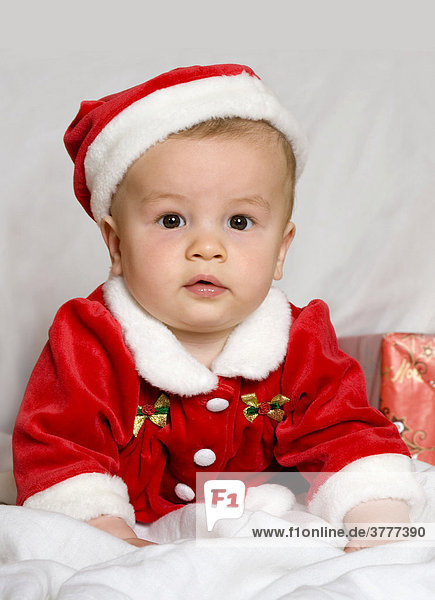Ein kleiner Junge  9 Monate alt  in einem Weihnachtsmann-Kostüm