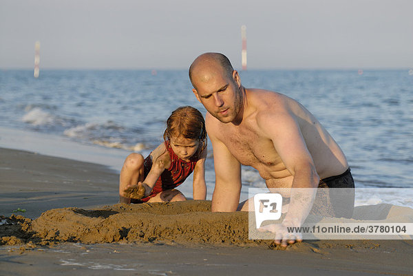 Familie baut eine sandburg am Strand