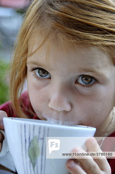 Kind trinkt Milch aus einer Tasse