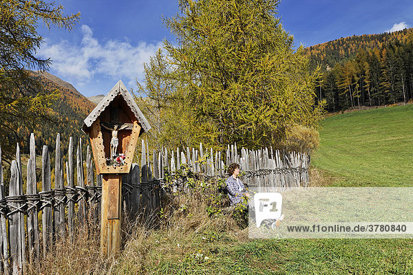 Female hiker rests beneath a wooden cross  Terenten  South Tyrol  Italy