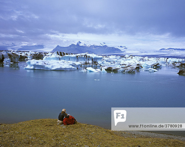 A couple enjoys the view to the glacier lake Breitharlon and the glacier Vatnajoekull  Iceland