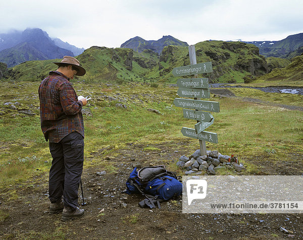 Woman studies map in front of a guidepost  Thorsmoerk  Iceland