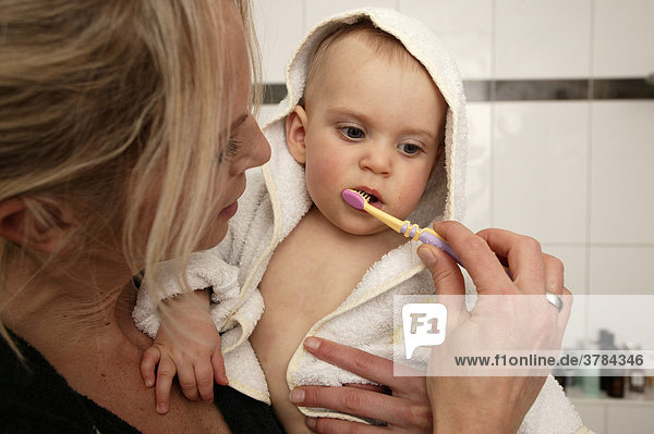 A mother brushes her baby's teeth