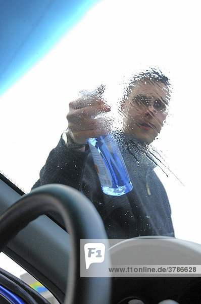 Mann reinigt die Windschutzscheibe eines Fahrzeugs