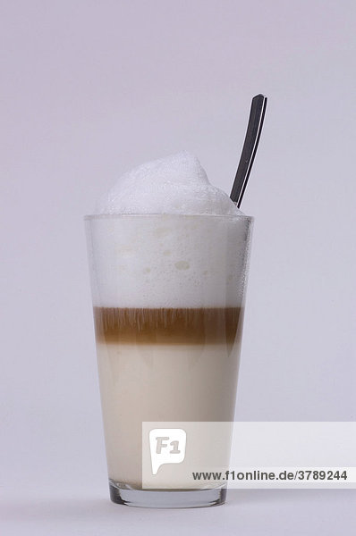 Milchkaffee in Glas mit Löffel